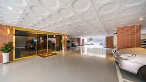 Ein modernes Gebäude mit einem markanten Dachdesign, Glasüren und einem Parkplatz mit Autos.