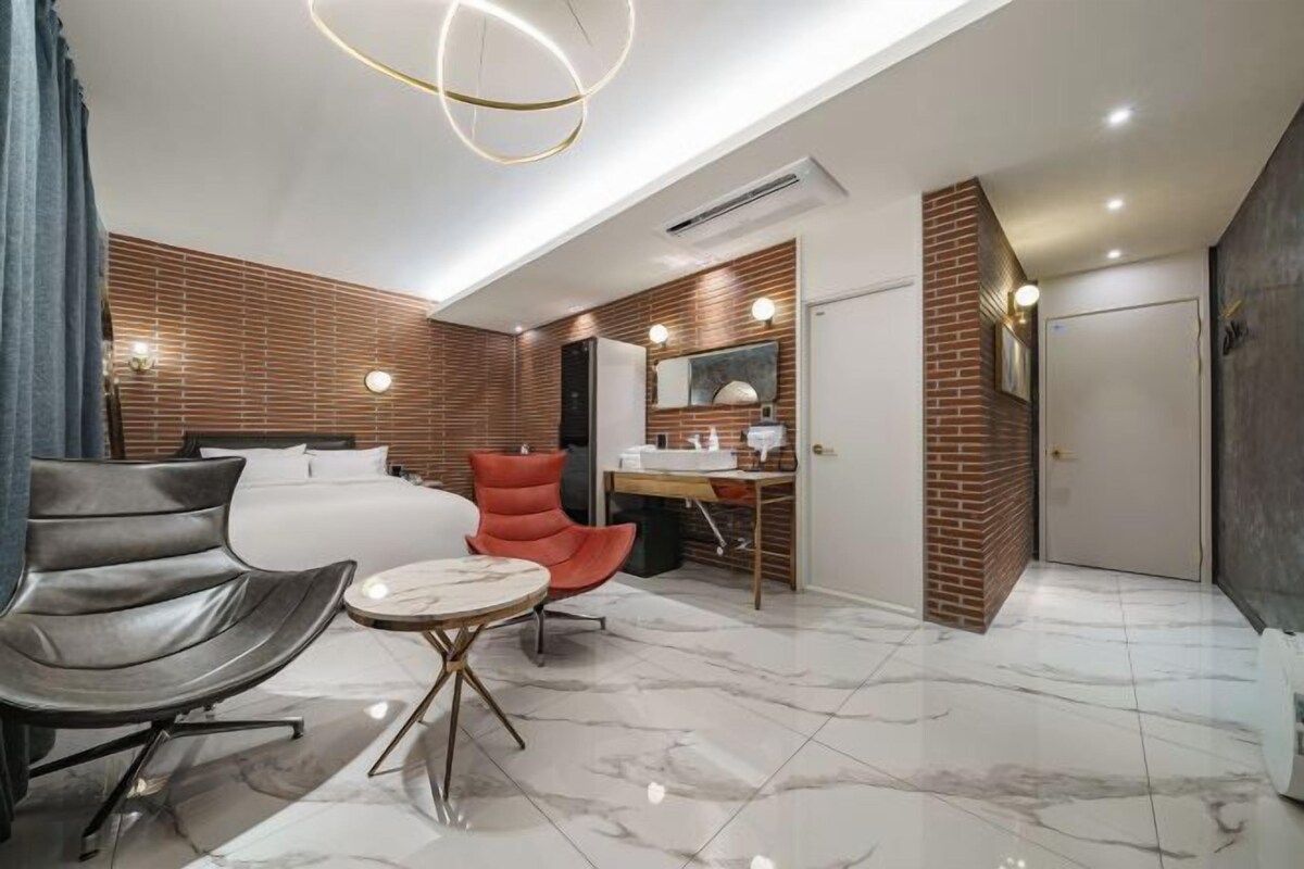 Una habitación de hotel moderna con una cama, un escritorio, una silla y una mesita.