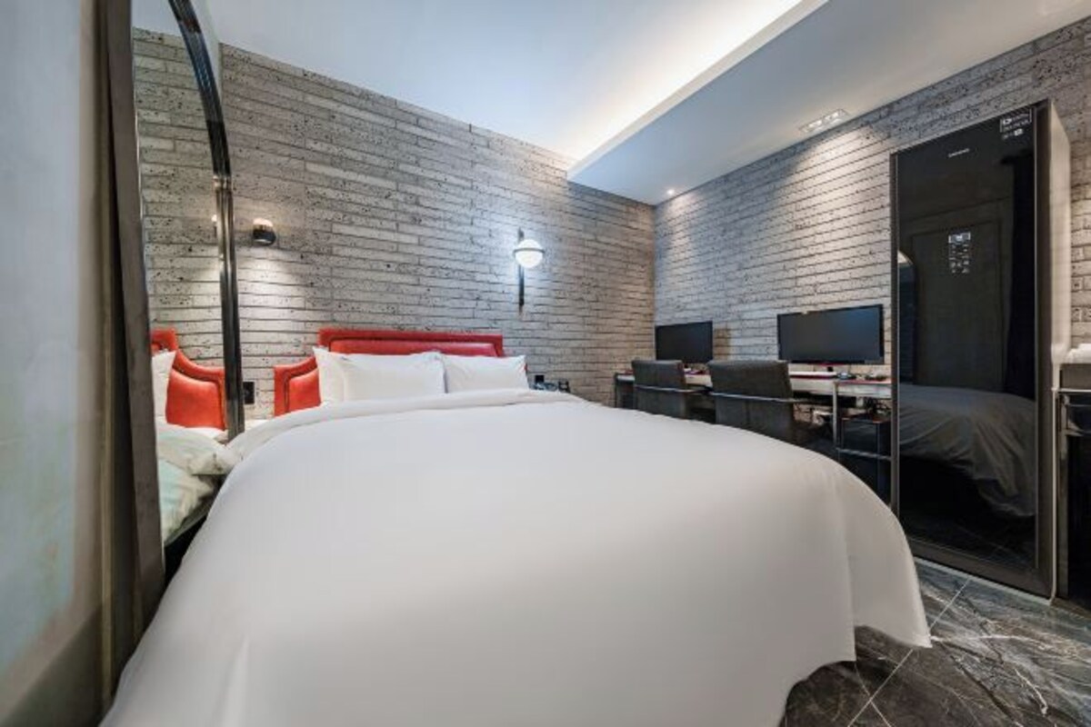 A modern hotel room with a large bed, a television, and a desk.