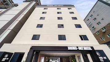 Ein mehrstöckiges Hotel mit modernem Design, das durch einen markanten Eingang und ein Schild mit der Aufschrift "BROWN - DOT HOTEL" gekennzeichnet ist.