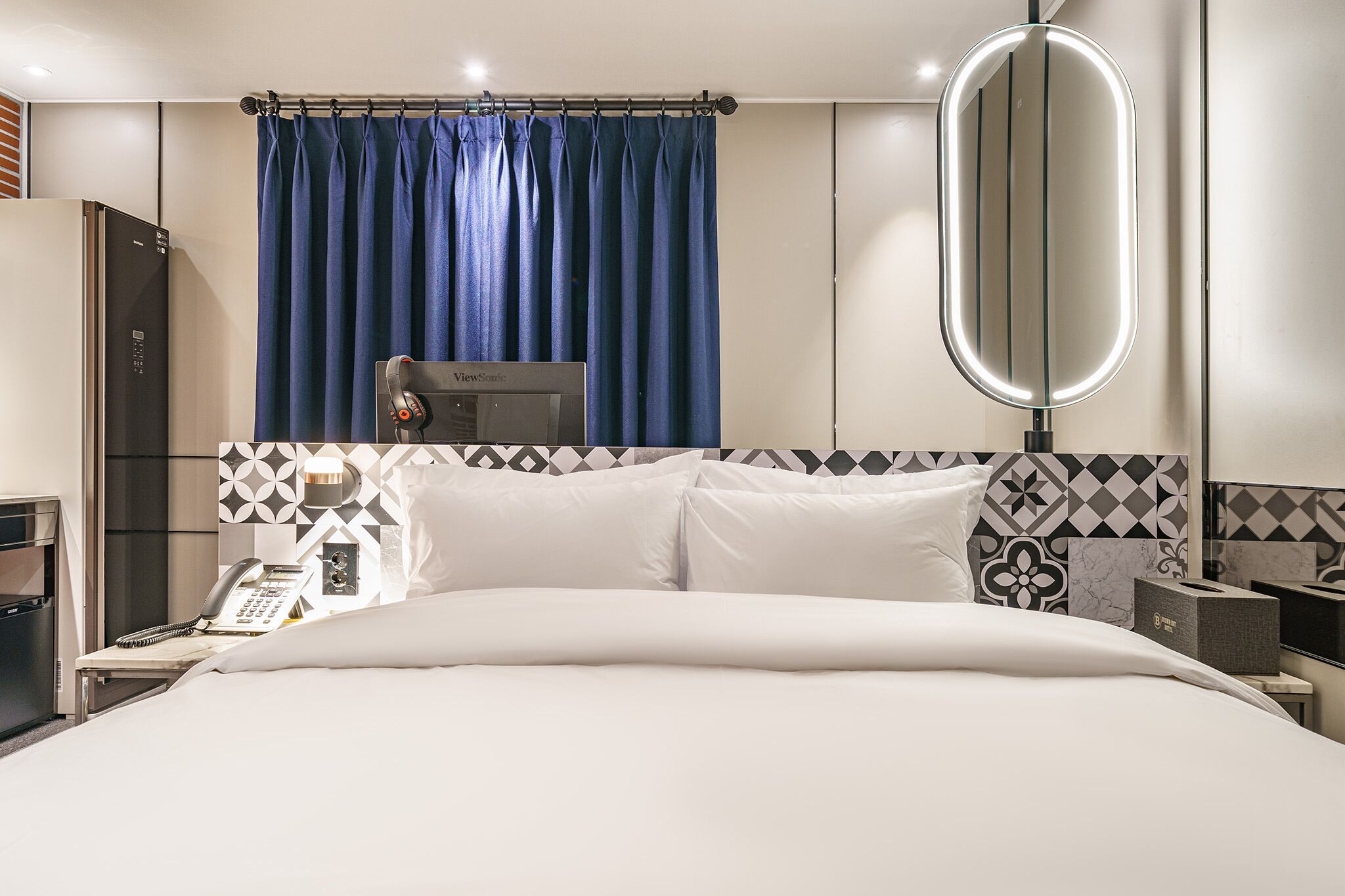 Una habitación de hotel con cama, teléfono, espejo Viewmount y armario.