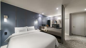 Ein modernes Hotelzimmer mit zwei Betten, einem Schreibtisch, einem Spiegel und einem Kleiderschrank.