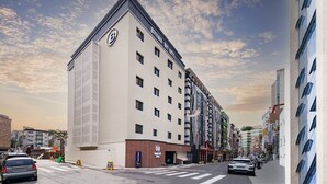 Ein modernes Hotel mit einem gut sichtbaren 'B'-Logo, mehreren Stockwerken und einer Ecklage mit Blick auf die Straße.