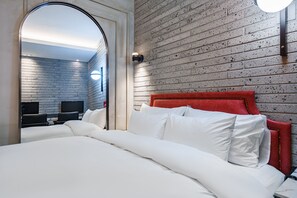 A hotel room with a brick-patterned wall, a red upholstered headboard, and a large bed with white bedding. - Brown-Dot Hotel Geomdan (Incheon)