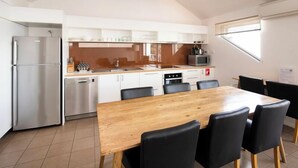 Une cuisine moderne avec une table à manger en bois et des chaises noires, un réfrigérateur en acier inoxydable et un four à micro-ondes.