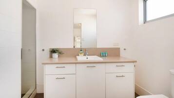 A bathroom with a white sink, mirror, and cabinets.