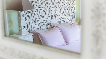 Une chambre à coucher avec une tête de lit décorative, une lampe de chevet et un lit agrémenté d’oreillers roses.
