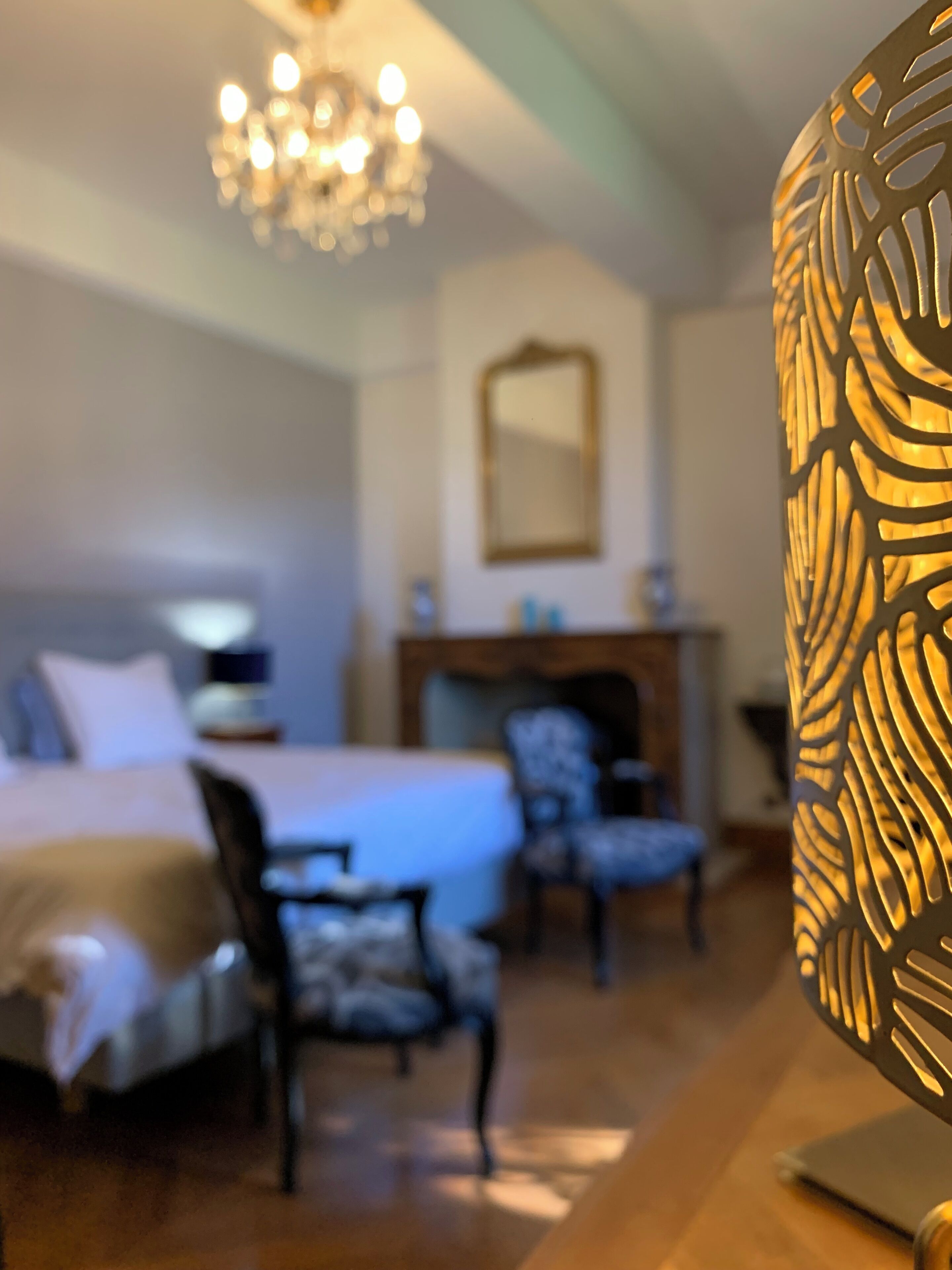 Una camera da letto con un letto, due sedie, una cassettiera e uno specchio appeso al muro.
