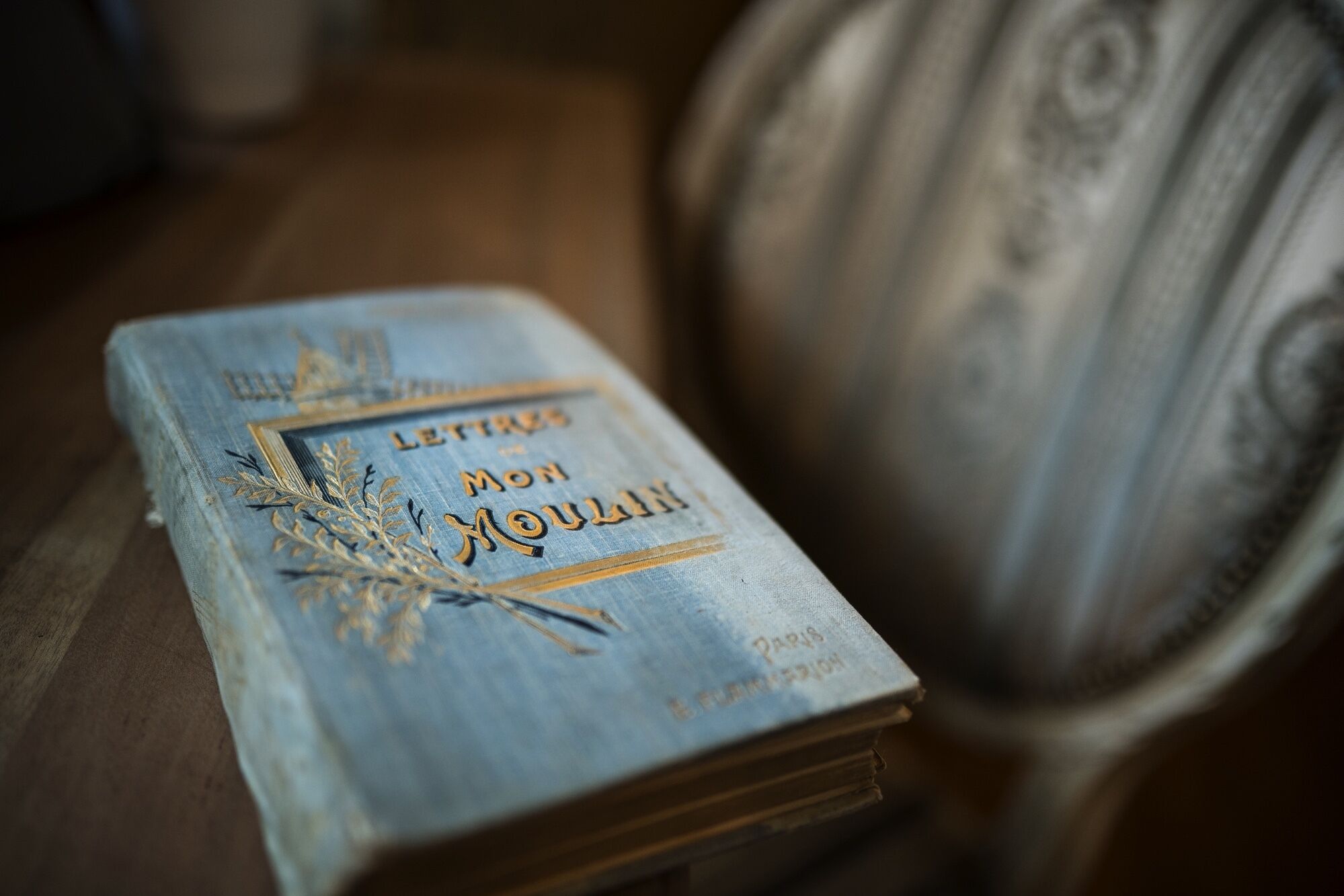 A book titled "Lettre à mon Moulin" with gold lettering and decorative elements, placed on a wooden surface.