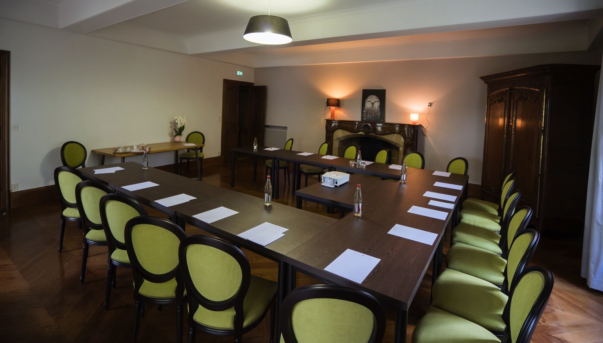 A conference room with a long table, chairs, a fireplace, and a television.