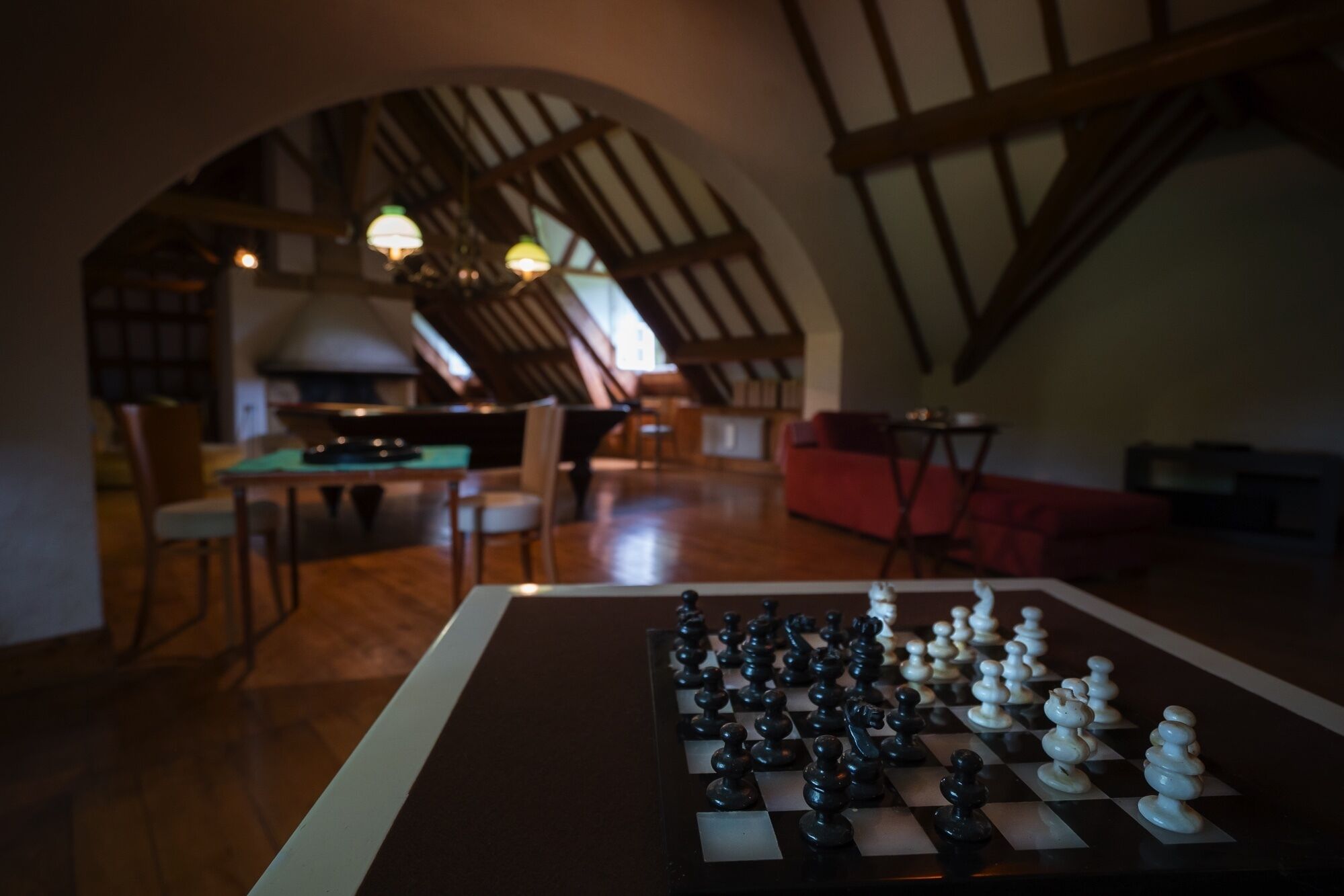 A cozy loft-style room with a chessboard, wooden beams, and a dining area.