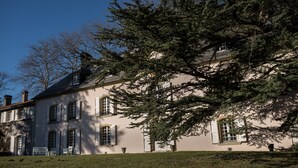 Een groot, historisch gebouw met veel ramen en een verzorgd gazon.