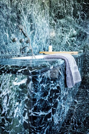 Un baño con lavamanos de mármol, una toalla y dispensador de jabón.