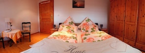 A bedroom with a floral bedspread, wooden wardrobe, and a small table with a chair. - Vacation apartment Landidylle (Birx)