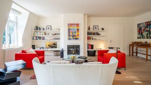 Ein modernes Wohnzimmer mit roter und weißer Möbel, einem Kamin und Bücherregalen.