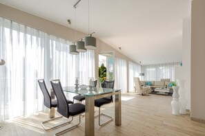 A modern living room with a glass dining table, black chairs, and a sofa.