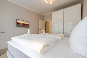 Habitación de hotel con una cama grande, un televisor de pantalla plana en la pared y una puerta que da a otra habitación.