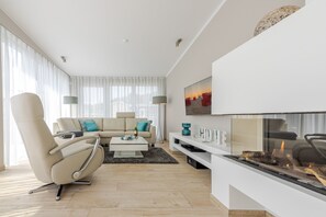 Una sala de estar moderna con un sofá, sillones, una mesa de centro y una chimenea.