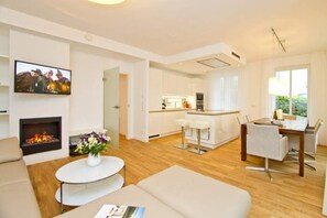 A modern living room with a fireplace, a dining area, and a kitchen. - Beach residences Bansin, Ostseepalais 01 (Heringsdorf)