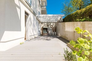 A narrow, covered outdoor corridor with a concrete wall on one side and a building entrance on the other. - Beach residences Bansin, Ostseepalais 01 (Heringsdorf)