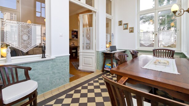 Uma sala de jantar com mesa de madeira, cadeiras e chão xadrez.