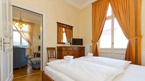 Quarto de hotel com uma cama grande, televisão sobre uma cômoda e vista para o exterior através de uma janela.