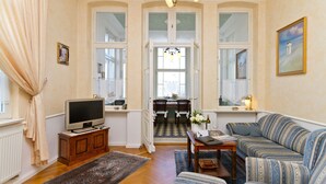 Uma sala de estar com sofá, televisão e um espaço de jantar com cadeiras e mesa.