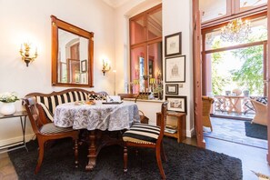 A dining area with a table set for two, surrounded by chairs, a mirror, wall-mounted lights, and framed pictures. - Villa Hintze, App. 06 (Heringsdorf)