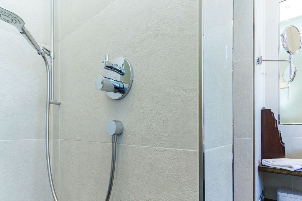 Une salle de bain avec une douche, des toilettes et un miroir.