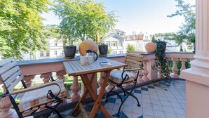 A balcony with a checkered floor, a table with a book, two chairs, and two large pots. - Villa Hintze, App. 06 (Heringsdorf)