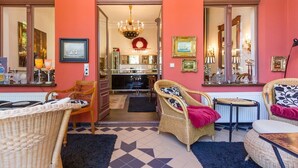 A room with wicker furniture, a chandelier, and a view into the kitchen. - Villa Hintze, App. 06 (Heringsdorf)