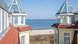 Un edificio frente al mar con vista a la playa, que destaca por su techo triangular y amplias ventanas.