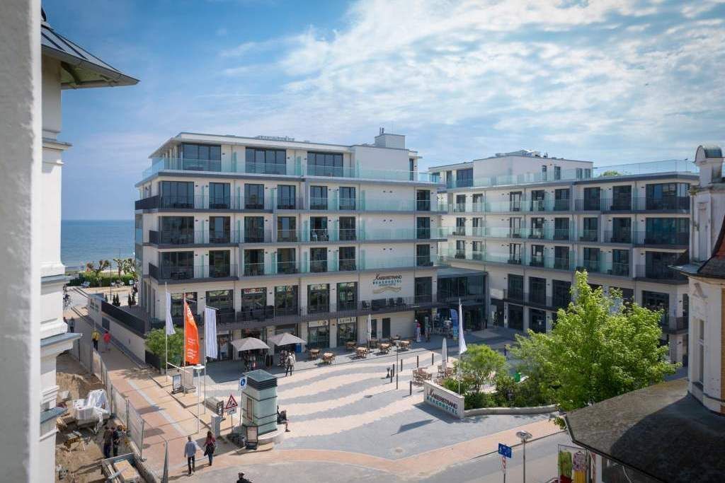 Un hotel su più piani con un cortile interno, posti a sedere all'aperto e vista sul mare.