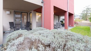 Un edificio con facciata rossa, posti a sedere all'aperto e un giardino curato.