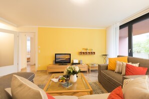 Un salon avec un canapé, une table basse, un téléviseur et un mur jaune.
