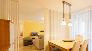 Un soggiorno moderno con zona pranzo, un divano, una TV e un tavolo con sedie.