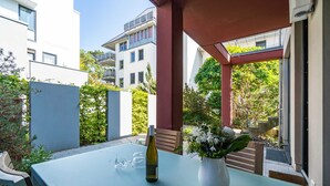 En terrasse med et bord, en vinflaske og en blomstervase.