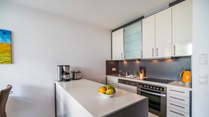 Et moderne køkken med hvide skabe, en indbygget ovn og en skål med frugt på øen.