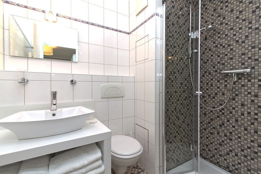 A modern bathroom with a white sink, a toilet, and a glass-enclosed shower area.