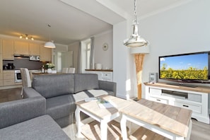 A modern living room with a grey sofa, wooden coffee table, and a television on a wooden stand. - Villa Frisia, App. 19 (Heringsdorf)