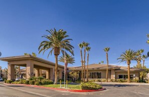 A hotel with a covered outdoor area, palm trees, and a clear blue sky.