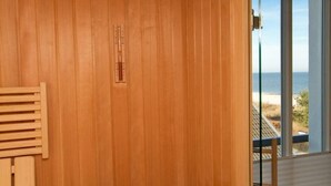 A room with wooden paneling, a wooden bench, and a view of the beach through large windows. - Beach residences Bansin, Ostseepalais 08 (Heringsdorf)