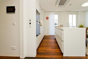 Une cuisine moderne avec des meubles blancs, un plancher en bois et un petit îlot central doté d’un évier.