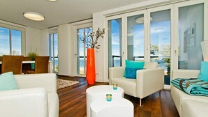 A modern living room with white furniture, a large window, and a view of the outdoors. - Beach residences Bansin, Ostseepalais 08 (Heringsdorf)