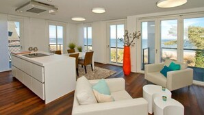 A modern interior with a kitchen, dining area, and seating space with a view. - Beach residences Bansin, Ostseepalais 08 (Heringsdorf)