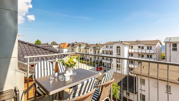 A balcony with a table and chairs, overlooking a residential area with houses. - Villa Linquenda, App. 6 (Heringsdorf)