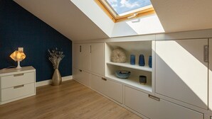 A room with a skylight, white cabinets, a wooden floor, and a vase with dried flowers. - Villa Linquenda, App. 6 (Heringsdorf)