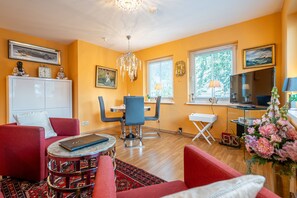 A living room with a red sofa, a blue chair, a small round table, a white cabinet, and a TV on a stand. - Inselstrand, App. 314 (Heringsdorf)