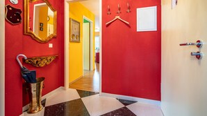 A hallway with red walls, a mirror, a coat rack, and a door. - Inselstrand, App. 314 (Heringsdorf)