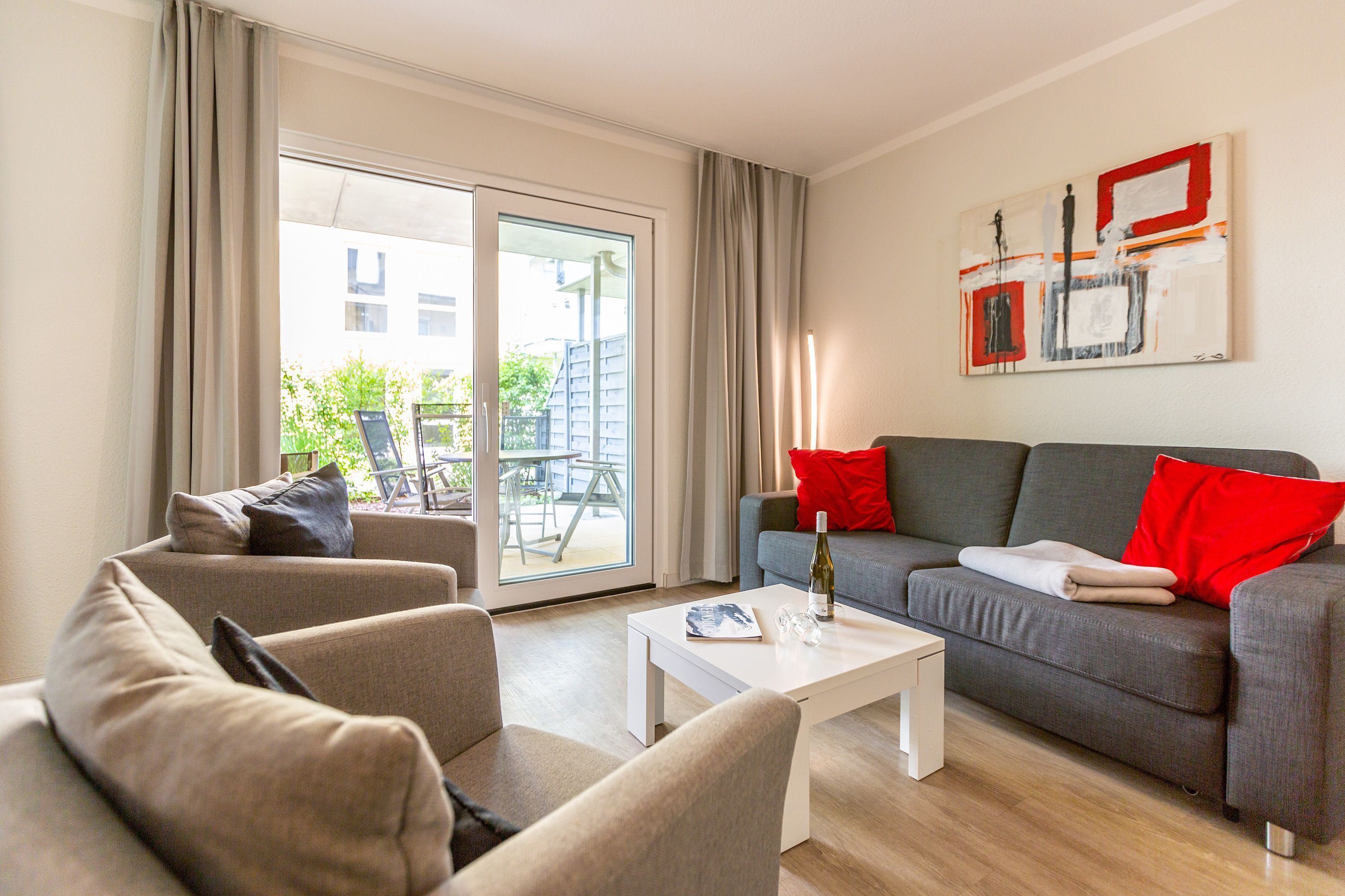 A modern living room with a grey sofa, a white coffee table, and a red and white abstract painting on the wall.